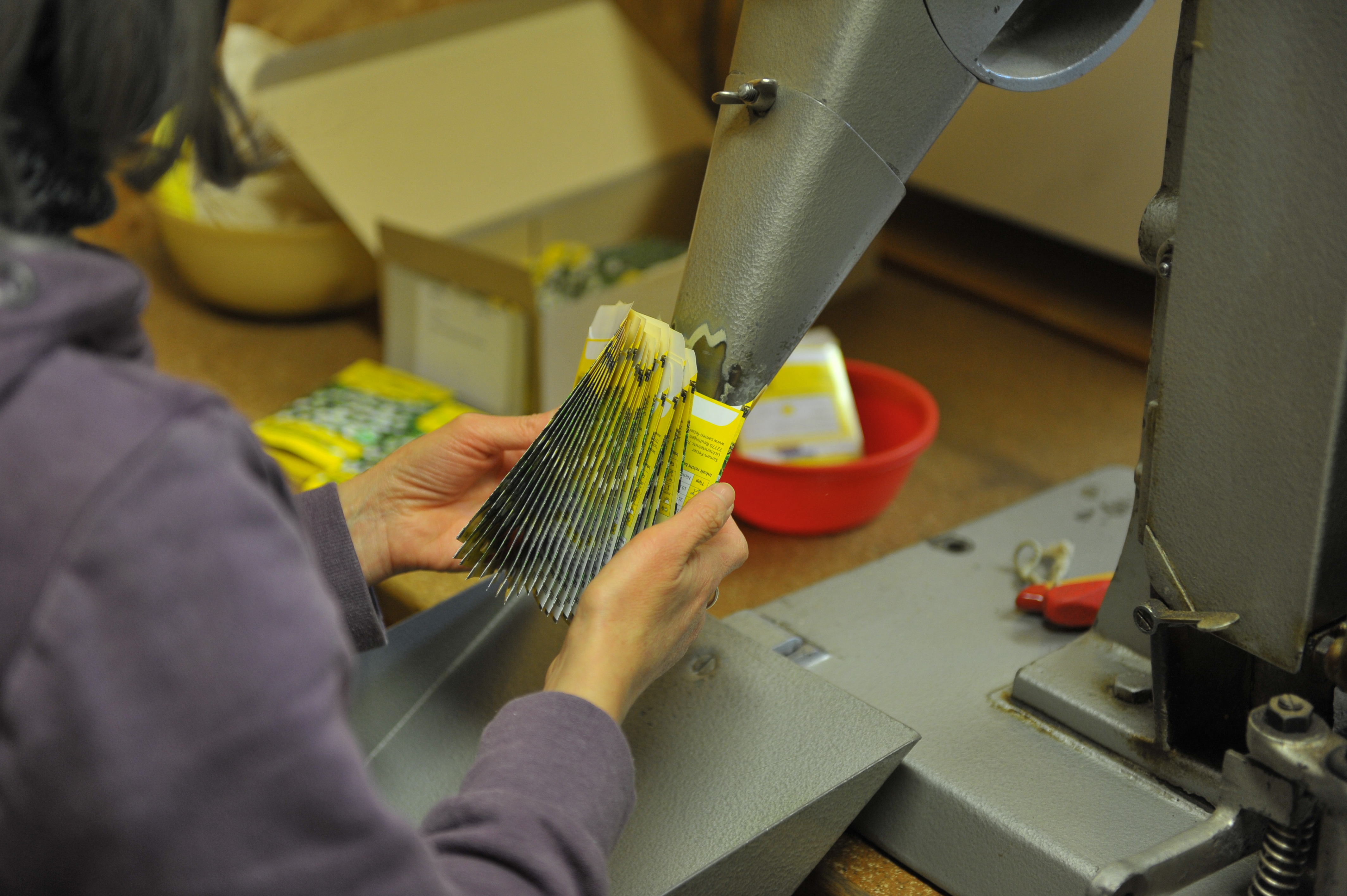 Eine Person hält mehrere Saatgutverpackungen zur Vorbereitung in der Fertigung.